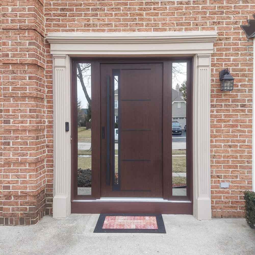 Front door of a residence with wide concrete frame, sidelight with reflective glass, a lockset, and a metal bar handle