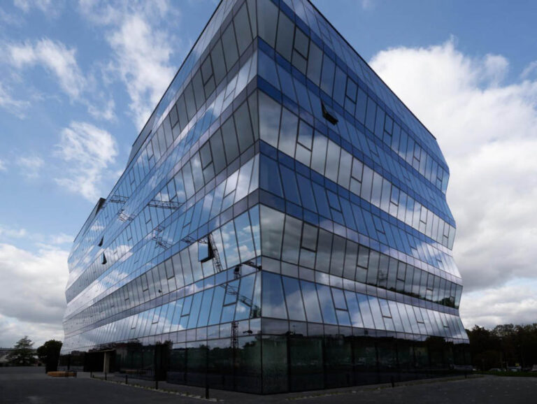 A futuristic architectural design of a commercial property, with its facets made of glass, with windows in a tilted position