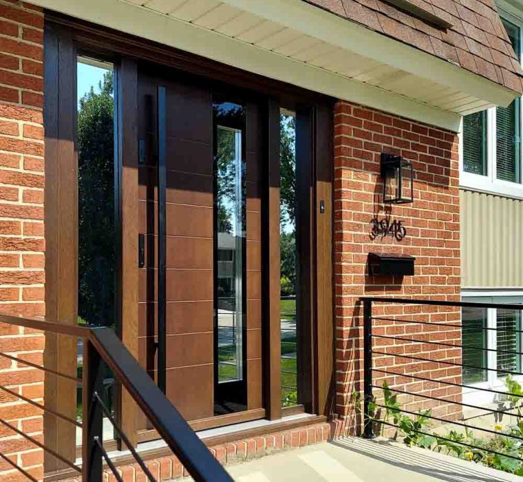 Main door of a house made of wood with two sidelights having reflective glass, a metal bar handle and two locksets