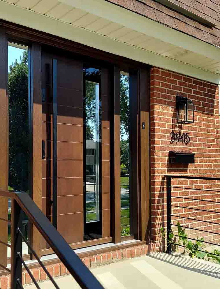 Main door of a house made of wood with two sidelights having reflective glass, a metal bar handle and two locksets